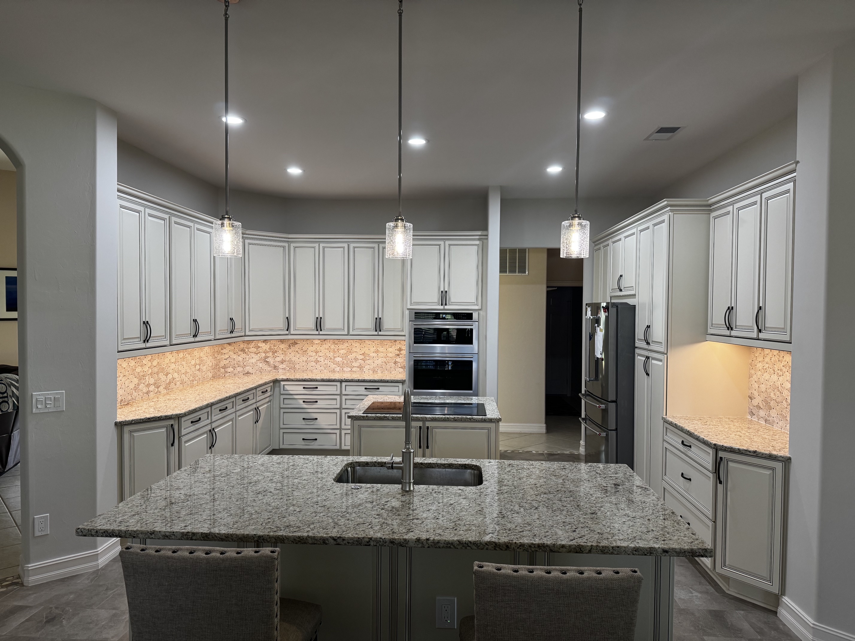 Completed kitchen remodel with wood cabinetry, tile backsplash, and a central island.