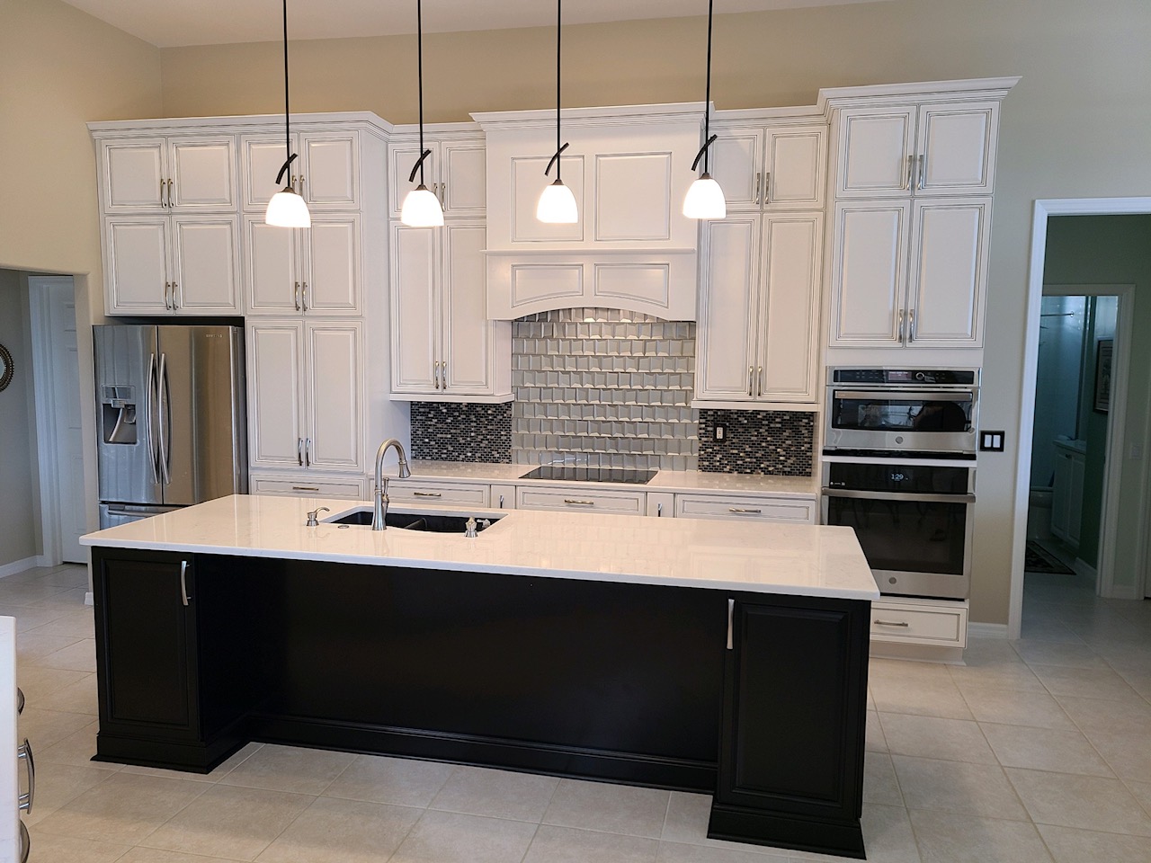 Completed custom kitchen with wood cabinetry, stone countertops, and a large central island.